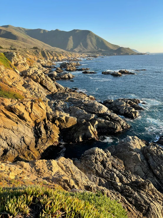 a lighthouse sitting on top of a cliff next to the ocean, craggy mountains, slide show, late afternoon, sharp spiky rocks