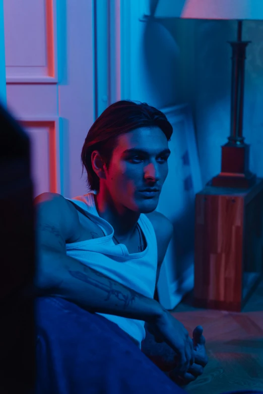 a man sitting on a couch in a living room, a colorized photo, inspired by Nan Goldin, trending on pexels, hyperrealism, adam driver, with blue light inside, pewdiepie, editorial model