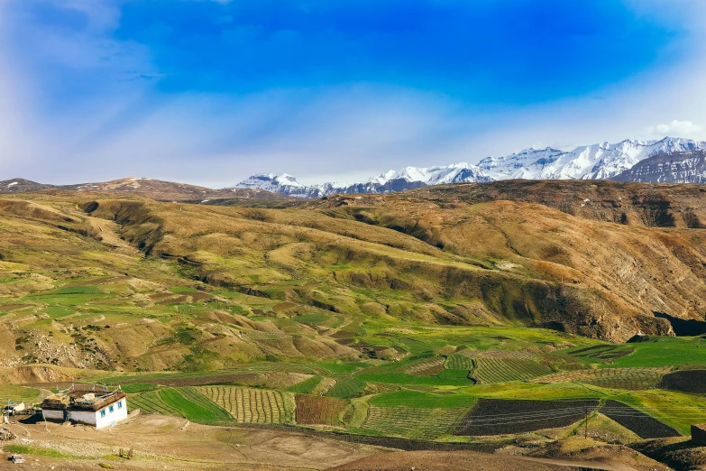 a small white house sitting on top of a lush green hillside, by Muggur, pexels contest winner, hurufiyya, snow capped mountains, nekro petros afshar, terraced orchards and ponds, panoramic