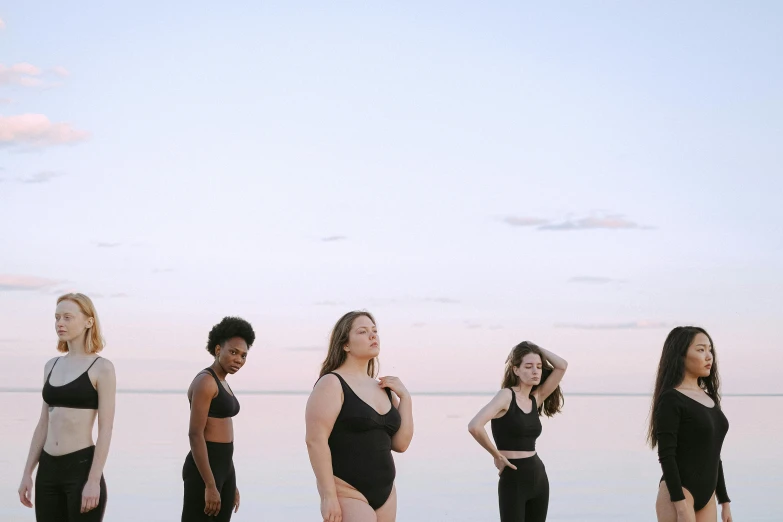 a group of women standing next to each other on a beach, unsplash, renaissance, wearing a black bodysuit, slightly overweight, float, looking off to the side