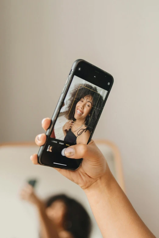 a woman taking a selfie with her cell phone, trending on pexels, black wavy hair with bangs, your personal data avatar, ashteroth, digital image