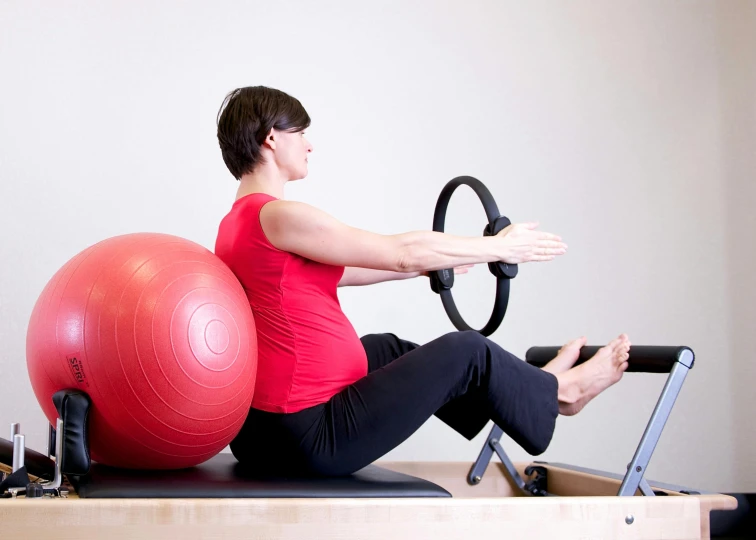 a woman sitting on a pilates with a red ball, a photo, by Arabella Rankin, private press, hoang lap, maternal, mid view, high detail photo