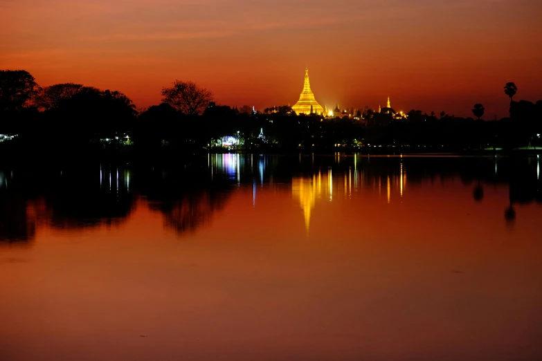 a large body of water with a building in the background, by Yosa Buson, pexels contest winner, glowing temple in the distance, reflective gradient, golden hues, phot