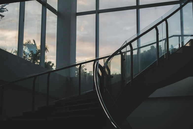 a person standing at the top of a set of stairs, inspired by Elsa Bleda, unsplash contest winner, modernism, large glass windows, dark academia aesthetics, stainless steal, stairs and arches