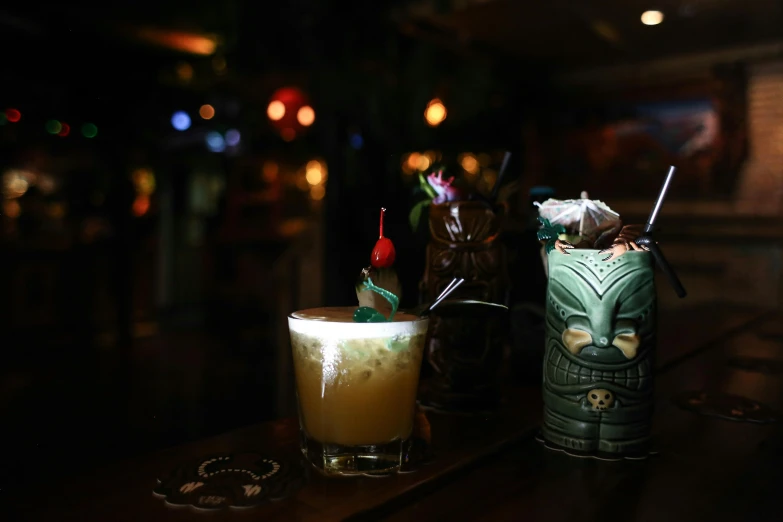a couple of drinks sitting on top of a wooden table, at night, profile image, tiki, in house