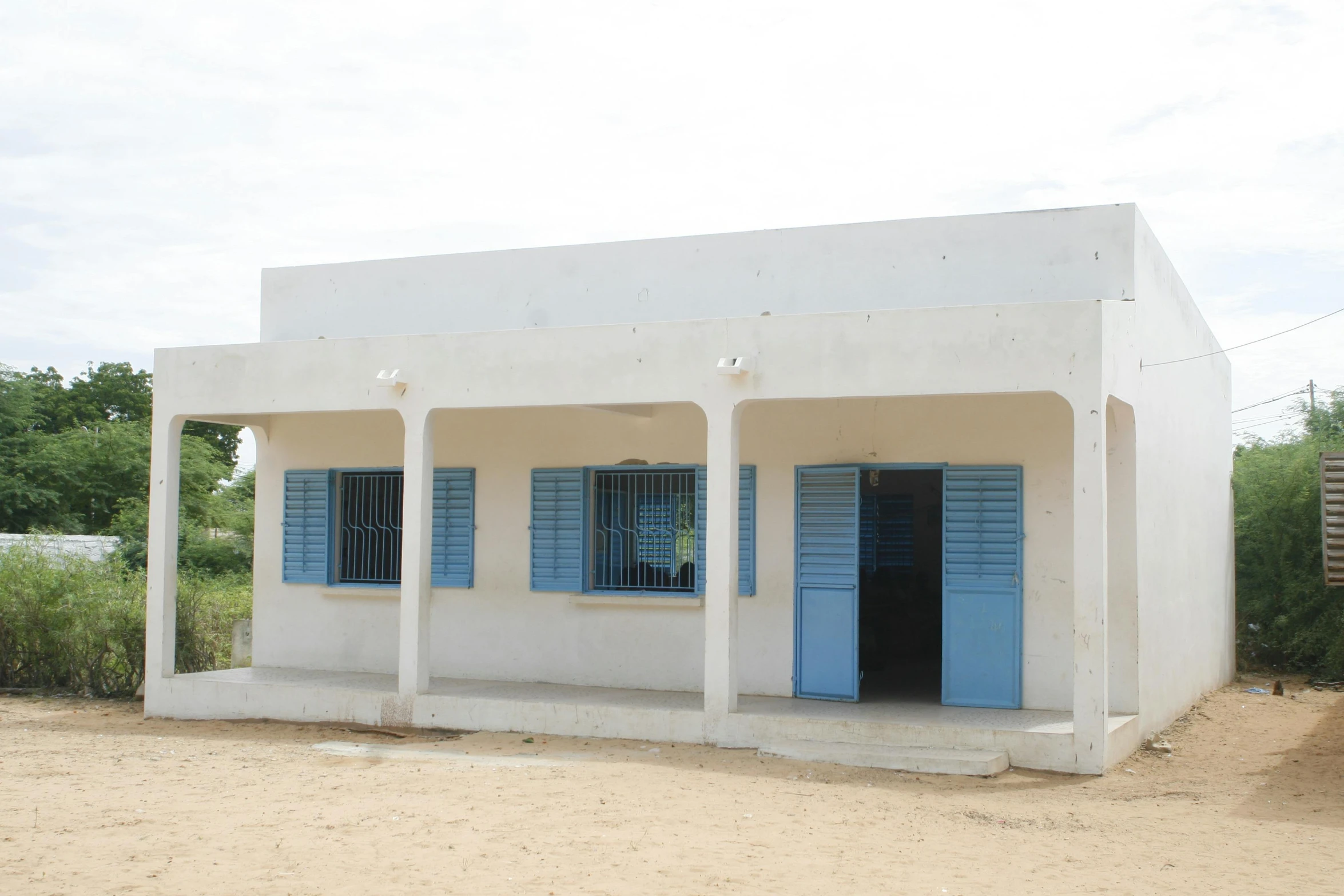 a small white building with blue shutters, by Daniel Lieske, northwest school, mamou - mani, inauguration, ground - level view, wide frontal view