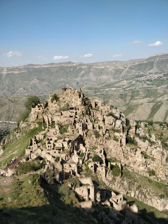 a group of people standing on top of a mountain, by Muggur, buildings carved out of stone, bird\'s eye view, mud and brick houses, byzantine ruins