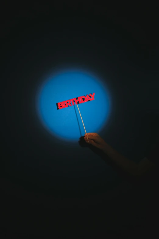 a person holding a lit up sign in the dark, an album cover, inspired by Bruce Nauman, unsplash, blue moon ray tracing, single long stick, blue and red two - tone, floating objects