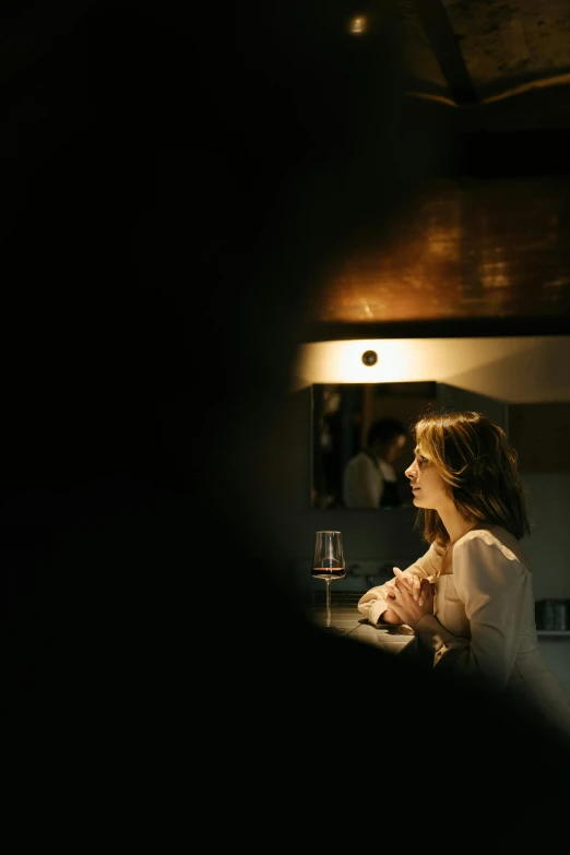 a woman sitting at a counter in a kitchen, a portrait, inspired by Nan Goldin, unsplash, reflecting light in a nightclub, elegant look, sydney hanson, slightly minimal