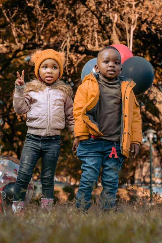 a couple of kids standing next to each other, by Arie Smit, pexels, instagram post, brown clothes, rosen zulu, celebrating