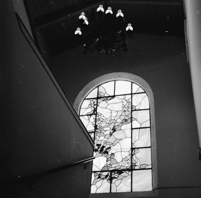 a black and white photo of a stained glass window, by Jan Rustem, light and space, coming down the stairs, with cobwebs, high ceiling, amethyst stained glass