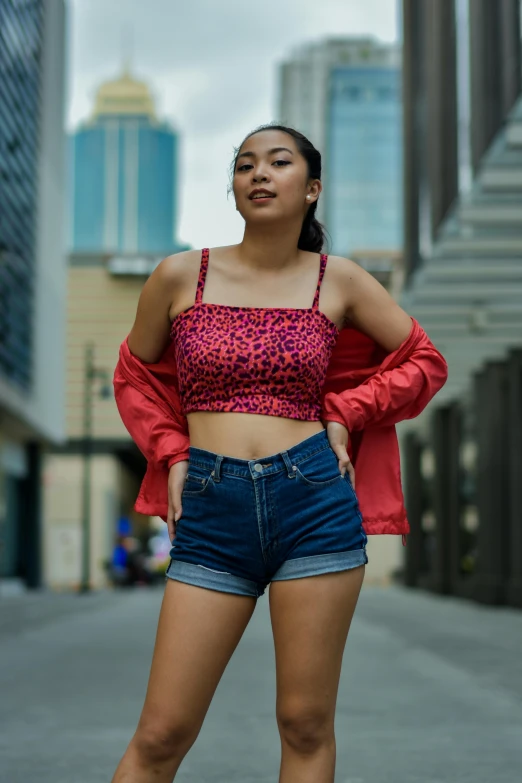 a woman standing in the middle of a city street, by Sven Erixson, pexels contest winner, croptop and shorts, cool red jacket, wearing a camisole and shorts, patterned clothing