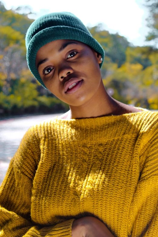 a woman in a yellow sweater and a green hat, trending on pexels, slide show, black teenage girl, serene expression, real-life brook