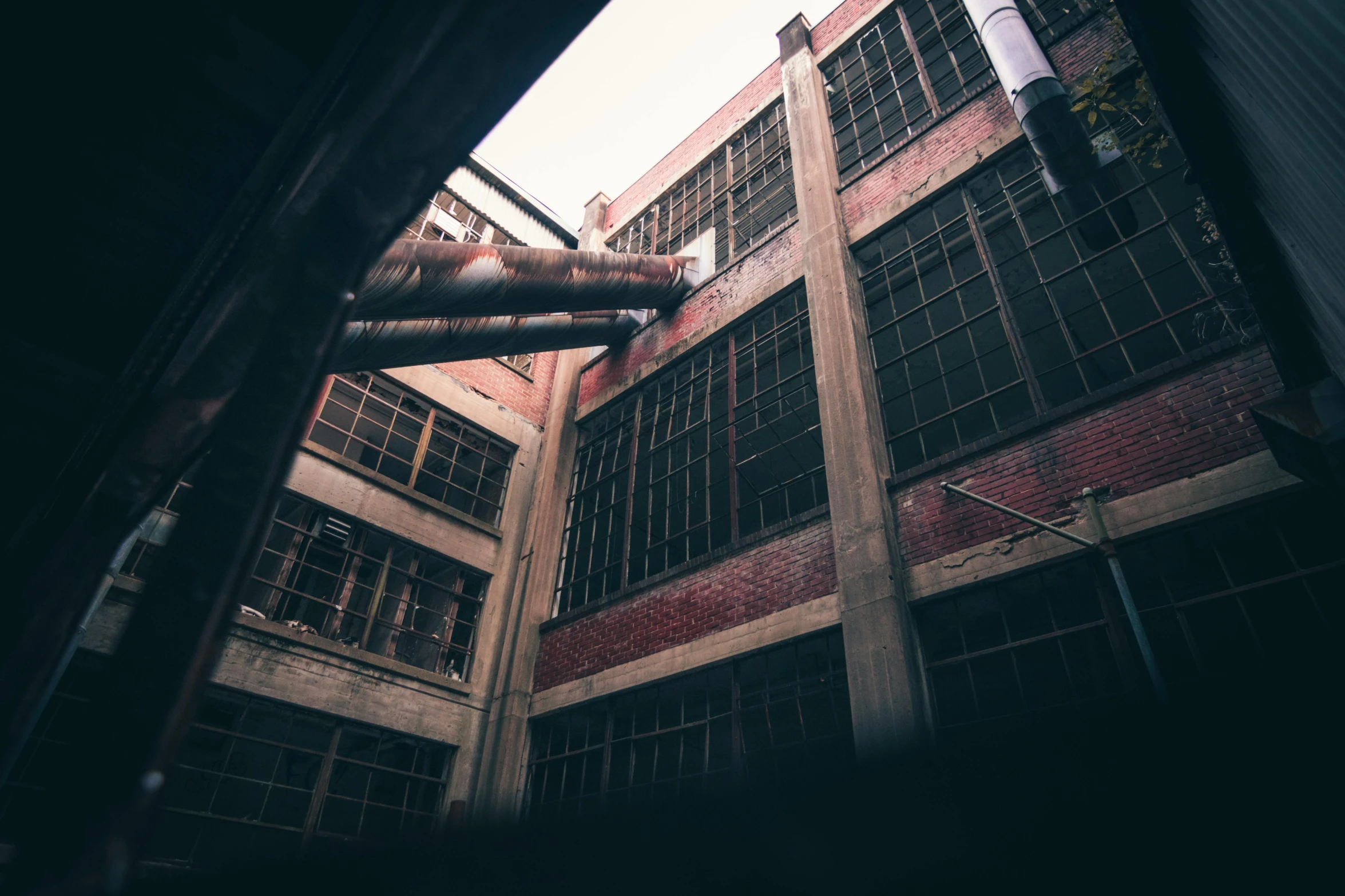 a very tall building with lots of windows, a photo, inspired by Elsa Bleda, pexels contest winner, graffiti, factory floor, ((rust)), mid air shot, mysterious exterior