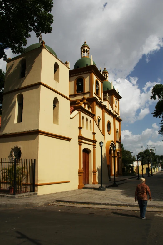 a person walking down a street in front of a church, inspired by Ceferí Olivé, baroque, cuban setting, square, golden, tula