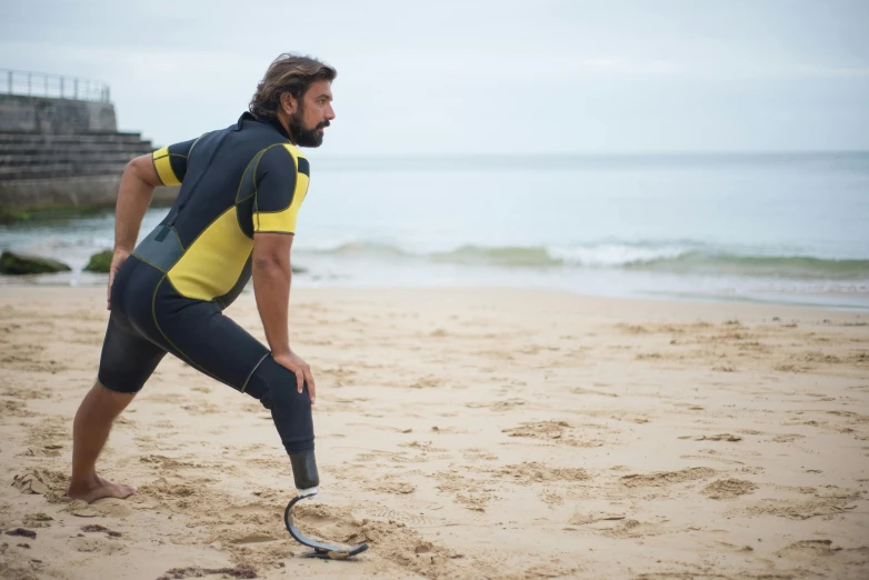 a man standing on top of a sandy beach, prosthetic, quicksilver, wearing fitness gear, seu madruga