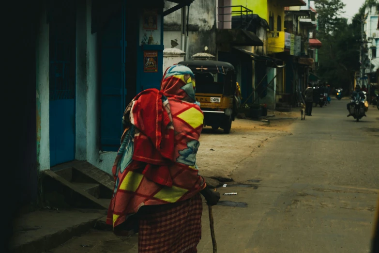 a woman is walking down the street with a cane, pexels contest winner, hyperrealism, bangladesh, colorful robes, post - apocalyptic city streets, provocative indian