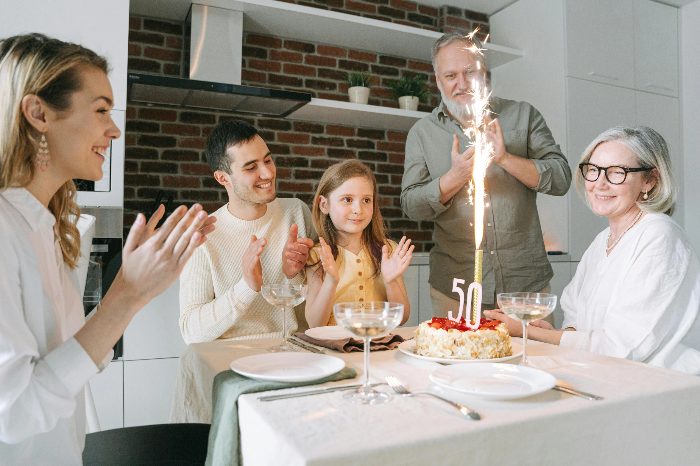 a group of people sitting around a table with a cake on it, 5 0 years old man, -step 50, fan favorite, families playing