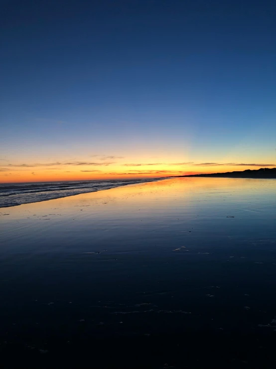 a large body of water sitting on top of a sandy beach, sunset ligthing, profile image, golden bay new zealand, multiple stories