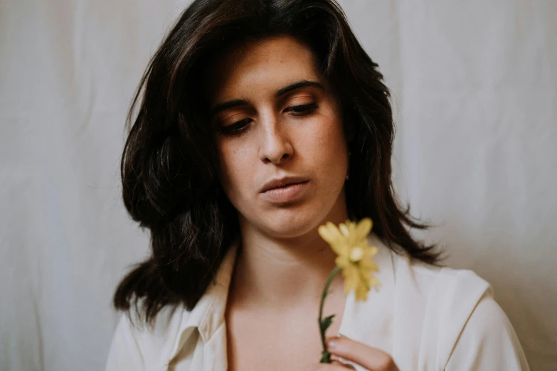 a woman in a white shirt holding a yellow flower, an album cover, pexels contest winner, charli bowater and artgeem, profile image, relaxed eyebrows, headshot profile picture