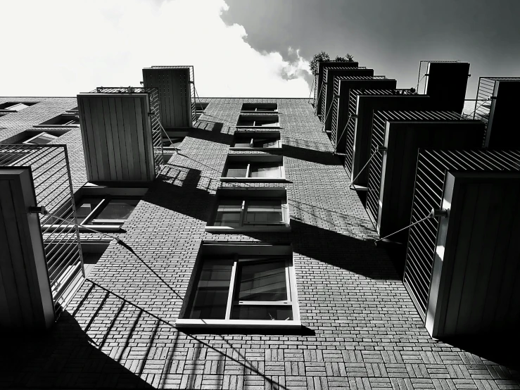 a black and white photo of a tall building, a black and white photo, inspired by André Kertész, unsplash, bricks, sunny day, eyelevel!!! view!!! photography, low dutch angle