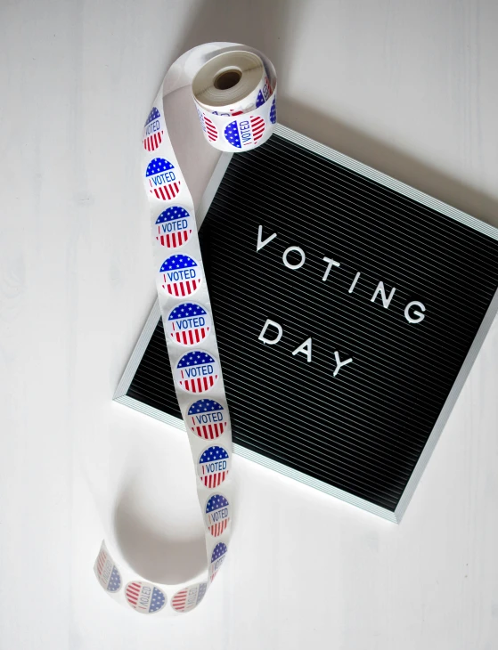 a sign that says voting day next to a ribbon, by Juliette Wytsman, pexels contest winner, square sticker, high resolution product photo, overlooking, long