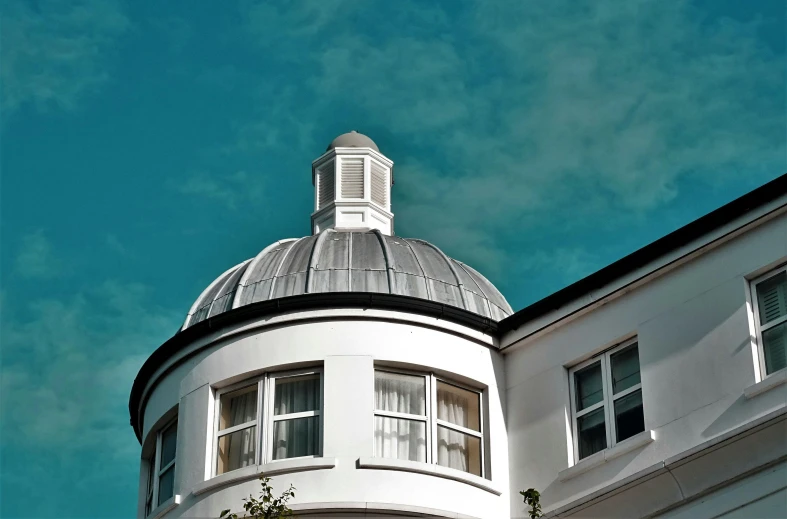 a clock that is on the side of a building, inspired by Rene Magritte, unsplash, berlin secession, rounded roof, esher, bay window, teal sky