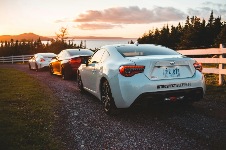 a couple of cars parked next to a white fence, unsplash, quebec, toyota supra, avatar image, group photo