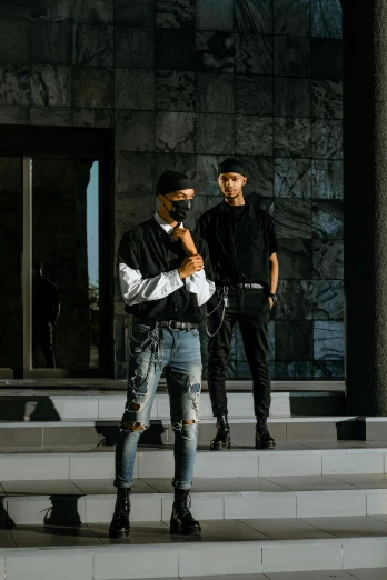 two men standing on the steps of a building, an album cover, pexels contest winner, techwear fashion, ( ( dark skin ) ), concert, full body picture