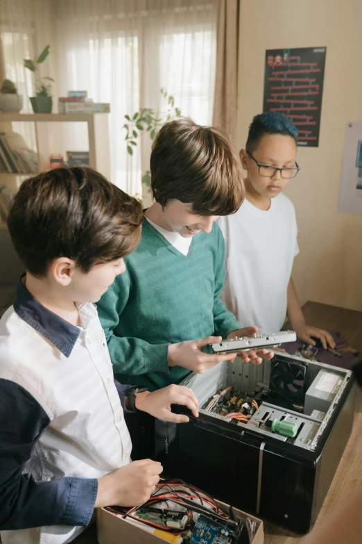 a group of children standing around a computer, hardware, aesthetic shot, ignant, school curriculum expert