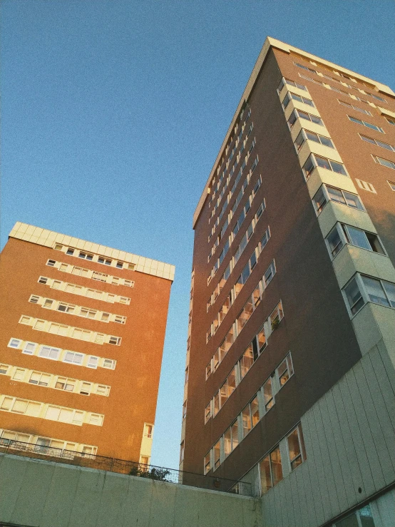 a couple of tall buildings sitting next to each other, an album cover, inspired by Thomas Struth, unsplash, brutalism, brown, hospital, sunfaded, high quality photo