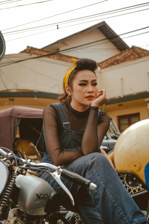 a woman sitting on the back of a motorcycle, inspired by Rudy Siswanto, trending on pexels, looking serious, vintage clothing, girl with messy bun hairstyle, square