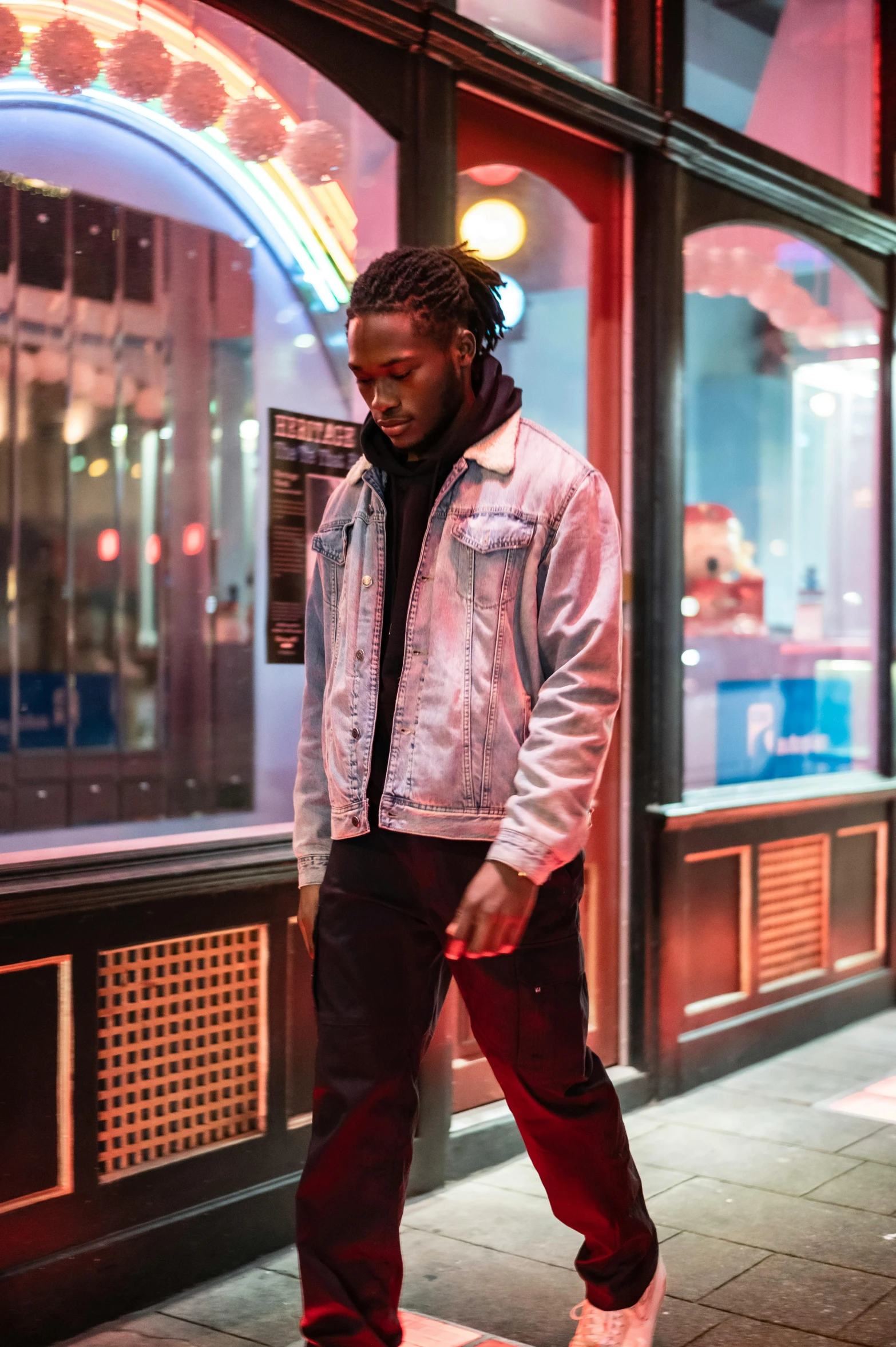 a man standing on a skateboard in front of a building, an album cover, trending on pexels, thick neon lights, wearing a jeans jackets, kendrick lamar, profile image