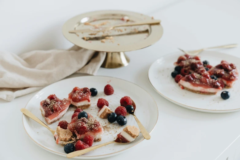 a close up of two plates of food on a table, by Emma Andijewska, trending on unsplash, berries, thin gold details, on white background, cake