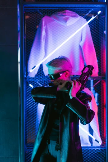 a man holding a gun in front of a display case, cyberpunk art, inspired by Ruth Deckard, trending on pexels, vergil, fashion neon light, xqc, futuristic sunglasses