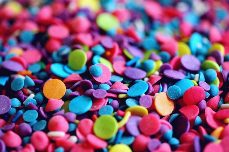 a pile of colorful sprinkles sitting on top of a table, a microscopic photo, pexels, made of dots, ((neon colors)), buttons, desaturated colours