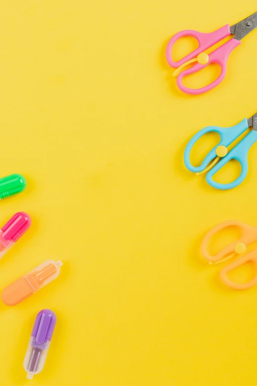 a group of scissors sitting on top of a yellow surface, colorful accents, educational supplies, neon accents, getty images