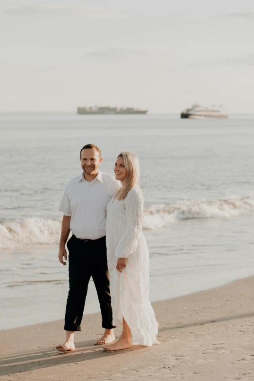 a man and woman standing on a beach next to the ocean, ships, professional photo, clear background, petros and leonid