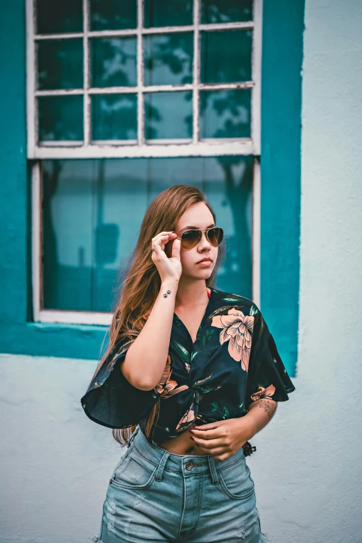 a woman standing in front of a window talking on a cell phone, inspired by Elsa Bleda, trending on pexels, graffiti, cool sunglasses, waring a hawaiian shirt, posing for a picture, sydney sweeney