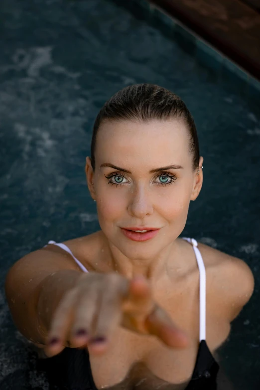 a woman in a pool pointing at the camera, a portrait, inspired by Anna Boch, unsplash, alison brie, square, spa, claire forlani