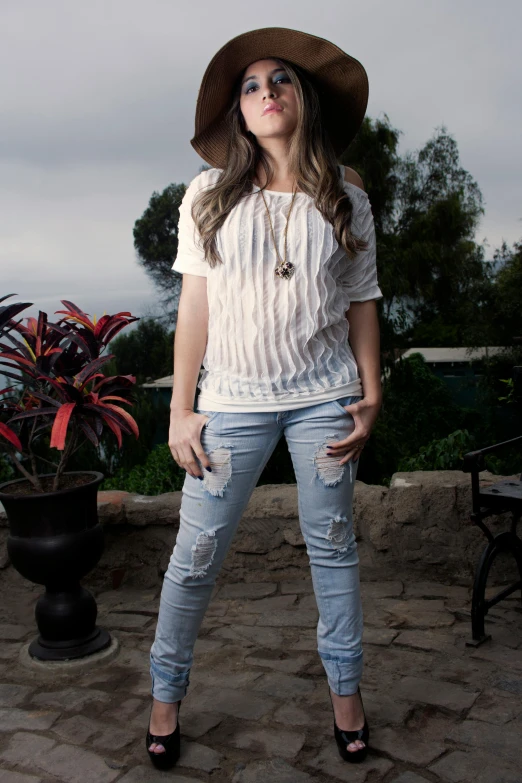 a woman in a hat is posing for a picture, white shirt and jeans, dressed in a ((ragged)), epk, cinematic full body shot