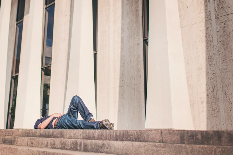 a man laying on the steps of a building, by Nina Hamnett, unsplash, college students, squinting at high noon, promo image, laying on her back