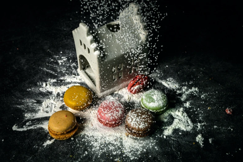 a bunch of pastries sitting on top of a table, a still life, by Lucia Peka, pexels contest winner, burst of powders, macaron, small houses, on black background