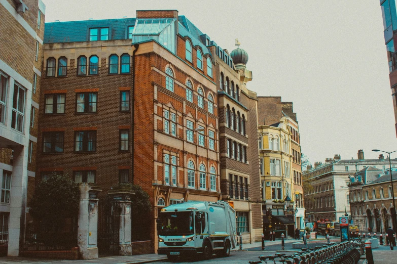 a bus driving down a city street next to tall buildings, by Nina Hamnett, pexels contest winner, art nouveau, brick building, 1 9 th century london, square, street of teal stone