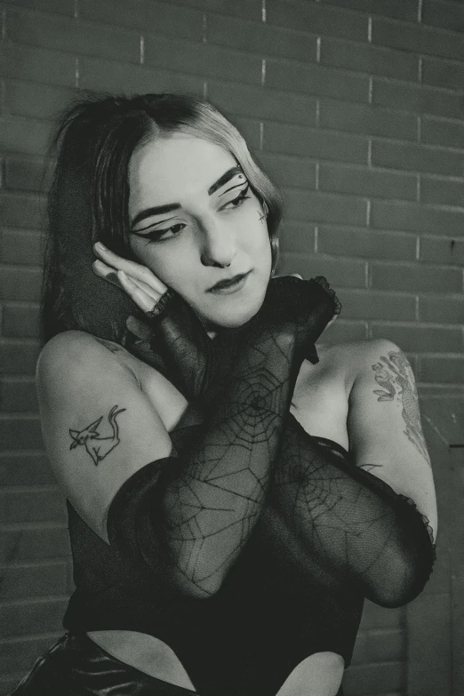 a black and white photo of a woman with tattoos, inspired by Elsa Bleda, featured on reddit, gothic art, long spider paws, 90's photo, cybergoth, shrugging