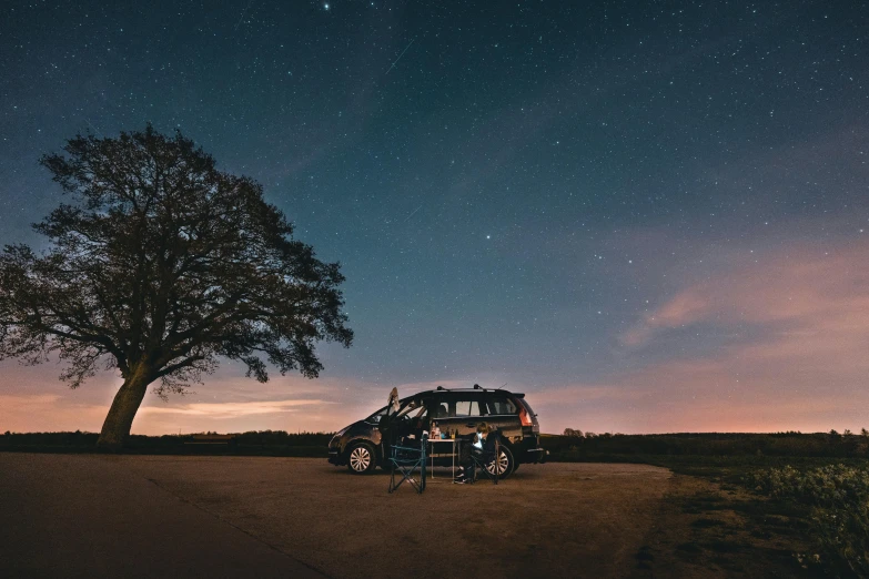 a van parked on the side of a road under a tree, by Jesper Knudsen, unsplash contest winner, stars and paisley filled sky, sitting on the beach at night, with a roof rack, panoramic shot