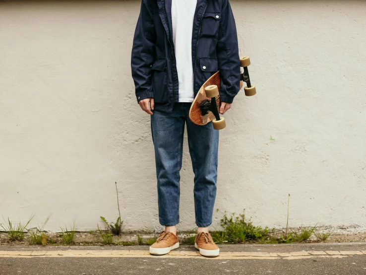 a man standing in front of a white wall holding a skateboard, wearing double denim, style of kanagawa, shoreline, a wooden
