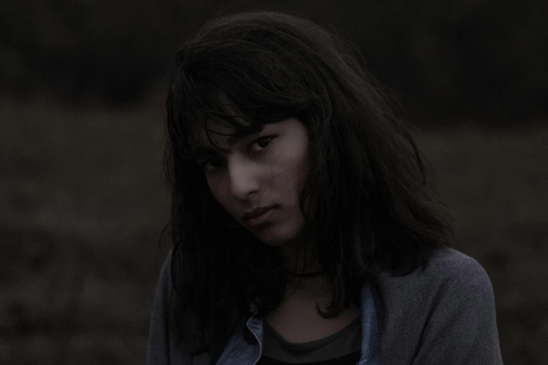 a woman standing in a field holding a frisbee, inspired by Elsa Bleda, finn wolfhard, dark and dim lighting, roadside, still image from tv series