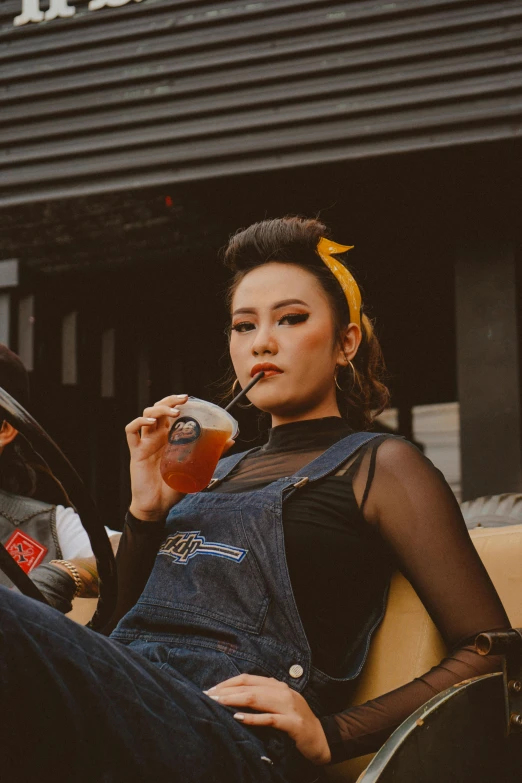 a woman sitting in a chair smoking a cigarette, an album cover, inspired by Ruth Jên, trending on pexels, lowbrow, drinking boba tea, rockabilly style, overalls, asian