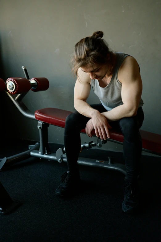 a man sitting on a bench in a gym, by Adam Marczyński, looking exhausted, lachlan bailey, profile image, distressed